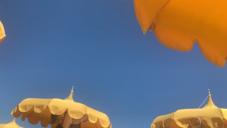 Low-angle-perspective-of-yellow-beach-umbrellas-on-blue-sky-background