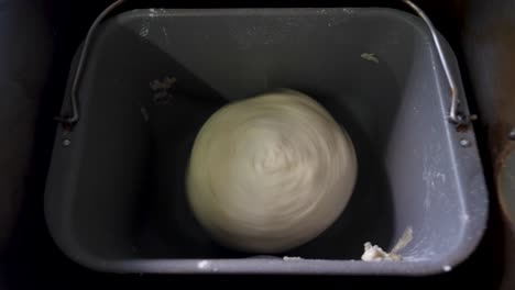 Round-ball-of-dough-spinning-in-bread-machine,-kneading-homemade-bread