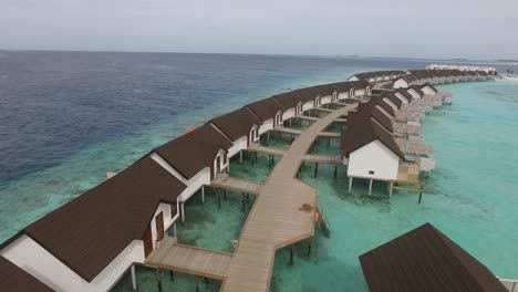 Drone-shot-above-water-villas-with-wooden-alley-in-a-Maldives-resort