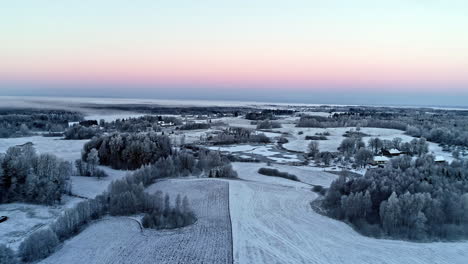 Farmland-fields-covered-in-fresh-snow-at-sunset---aerial-flyover