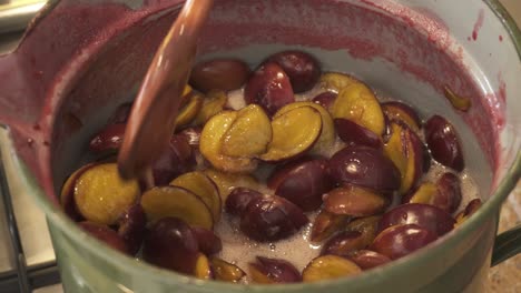 Cooking-And-Stirring-Homemade-Plum-Jam-In-Preserving-Pot-Using-Wooden-Spoon