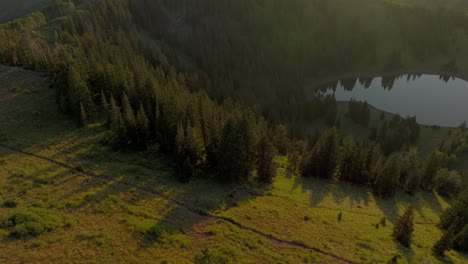 Aerial-over-backcountry-mountain-range,-lake,-and-forest-at-sunset