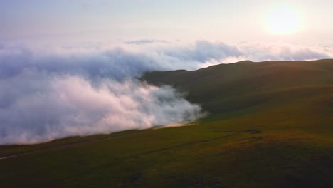 Clouds-And-Fog-Creeping-Over-Mountain-Valley-At-Sunset,-Aerial-View-From-Drone