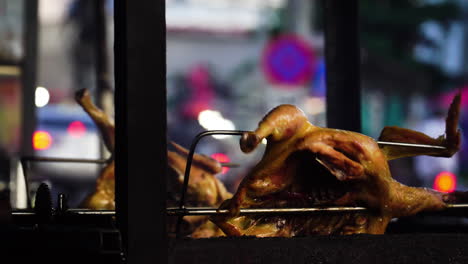 Vietnamese-duck-roasting-on-spinning-grill,-city-traffic-in-background