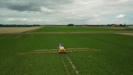 Flying-a-drone-behind-a-tractor-with-a-pull-type-sprayer-driving-on-a-cultivated-field