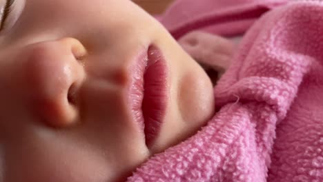 A-close-up-shot-of-a-baby-wearing-a-pink-woolen-cloth-sleeping-on-the-bed