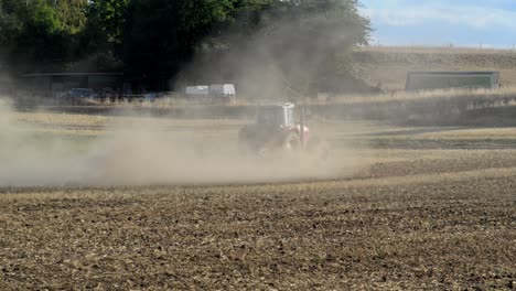 Red-tractor-plowing-a-dry-field-after-months-without-rain-causing-huge-amounts-of-dust-being-swirled-up