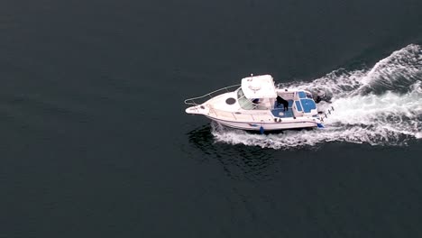 Ein-Weißes-Motorboot,-Das-Mit-Hoher-Geschwindigkeit-Auf-Ruhigem-Wasser-Dahinfährt---Luftverfolgung