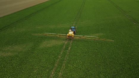 Flying-behind-a-tractor-with-a-pull-type-sprayer-traveling-in-a-straight-line-spraying-crop-protection-products