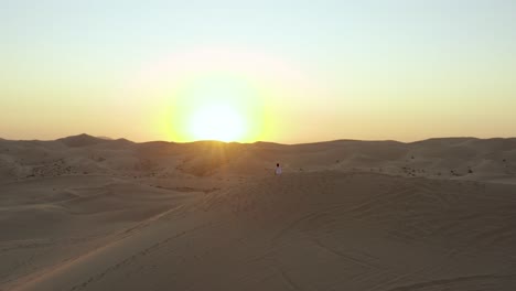 Happy-morning-sand-dune-sunrise-female-sitting-on-mound-embracing-sun-rays