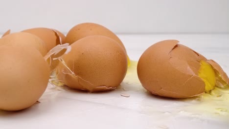 Brown-eggs-drop-on-counter-top,-shells-crack-and-spill-in-slow-motion