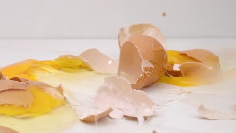 Brown-eggs-fall-onto-counter,-eggshells-crack-open-and-egg-yolks-and-whites-make-a-mess-in-slow-motion