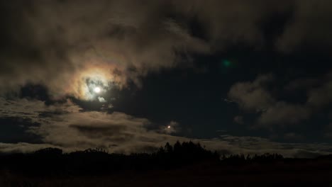 Bright-full-moon-in-night-sky-with-clouds-passing-by,-timelapse