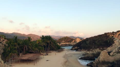 People-Walking-At-Maruata-Beach,-Remote-Sandy-Beach-With-Rocky-Landscape-In-Michoacan,-Mexico