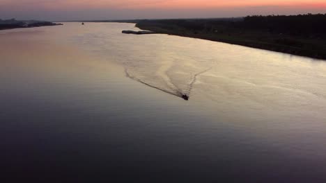 Small-motorboat-traveling-across-the-Paraguay-River-at-sunset