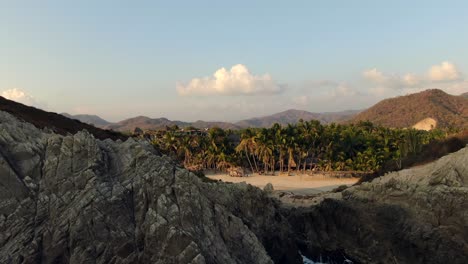 üppige-Palmen-Und-Wellen,-Die-An-Einem-Sonnigen-Nachmittag-In-Michoacan,-Mexiko,-Auf-Riesige-Felsbrocken-In-Playa-Maruata-Spritzen