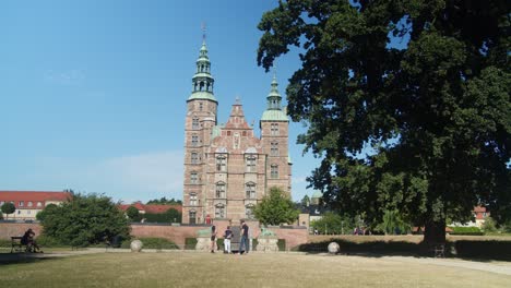 Rosenborg-Slot-with-a-huge-tree-in-the-foreground-in-Kongens-Have,-Copenhagen,-Denmark