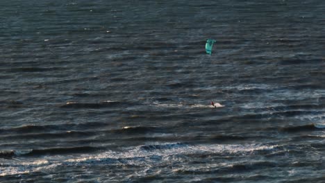 Kitesurfer,-Der-Bei-Windigem-Wetter-Und-Sonnenuntergang-Auf-Trüben-Dunklen-Wellen-Reitet