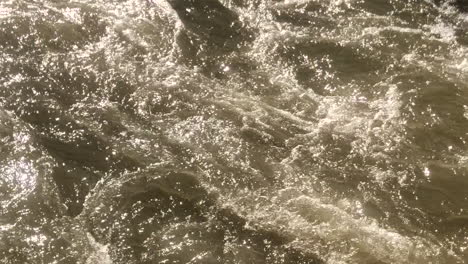Close-up-on-shiny-and-frothy-river-water-under-sunlight-on-a-sunny-day