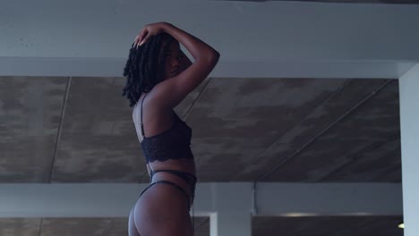 Low-angle-view-of-a-young-black-woman-wearing-lingerie-in-a-parking-garage