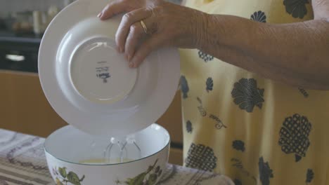 An-elderly-woman-is-mixing-with-electric-whips-the-ingredients-for-a-chocolate-cake