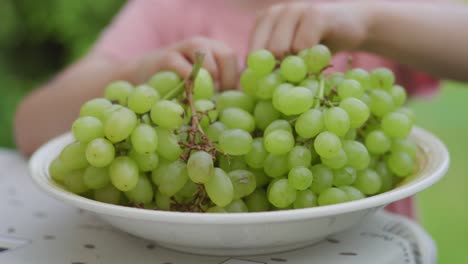 A-young-toddler-girl-is-eating-green-grapes-outside-during-the-summer