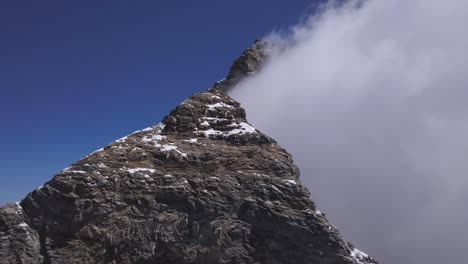 Matterhorn-Gipfel-Mit-Wolken,-Die-Eine-Seite-Verstecken,-Und-Dahinter-Ein-Klarer-Blauer-Himmel