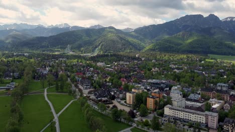 Flyover-of-Zakopane,-Poland,-a-resort-town-village-with-traditional-Goral-architecture-near-the-Polish-Tatra-mountains,-farmland,-forests,-Giewont-peak-and-Great-Krokiew-Ski-Jump---4K-Tracking-Forward