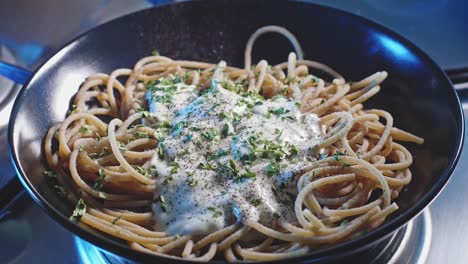 Gekochte-Spaghetti-nudeln-In-Einem-Teller-Mit-Griechischer-Joghurtsoße,-Garniert-Mit-Gehackter-Petersilie-Und-Schwarzem-Pfeffer