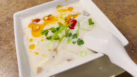 Tom-Kha-Gai-Thai-Soup-in-a-white-bowl,-closeup-shot