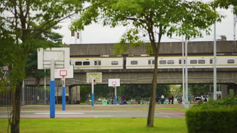 öffentlicher-Park-Mit-Basketballplätzen-Und-Einem-Zug,-Der-Im-Hintergrund-In-Der-Stadt-Taipeh,-Taiwan,-Vorbeifährt