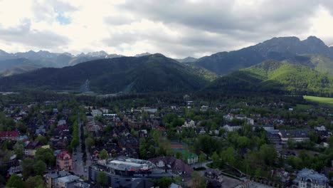 Flyover-of-Zakopane,-Poland,-a-resort-town-village-with-traditional-Goral-architecture-near-the-Polish-Tatra-mountains,-farmland,-forests,-Giewont-peak,-and-Great-Krokiew-Ski-Jump---4K-Panning-Right