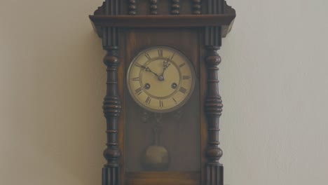 Antique-grandfather-clock-hanging-on-a-wall-of-a-rose-colored-house