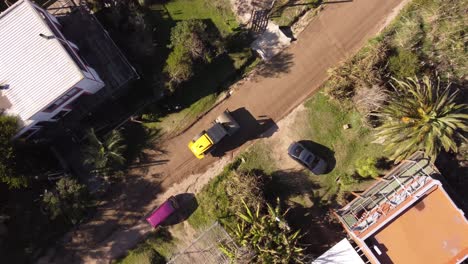Aerial-top-down-circling-view,on-yellow-leveling-machine-working-on-construction-of-new-road-in-residential-area-of-Uruguay