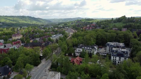 Flyover-of-Zakopane,-Poland,-a-resort-town-village-with-traditional-Goral-architecture-near-the-Polish-Tatra-mountains,-farmland,-forests,-valley,-flying-North-from-Poland's-border-4K-Tracking-Forward