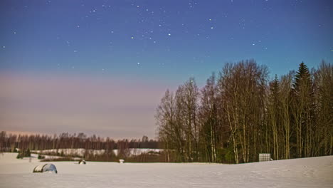Timelapse-shot-of-snowy-winter-field-with-frozen-hay-bales-with-stars-visible-in-the-night-sky