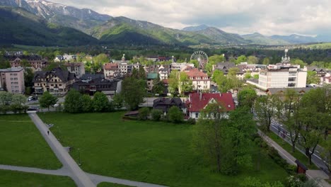 Flyover-of-Zakopane,-Poland,-a-resort-town-village-with-traditional-Goral-architecture-near-the-Polish-Tatra-mountains,-carousel,-forests,-Giewont-peak-and-Great-Krokiew-Ski-Jump---4K-Sweeping-Forward