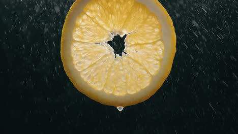 Fresh-Orange-Slice-Splashed-by-Water-Droplet-Mist-with-Liquid-Drip-in-Slow-Motion-Backlit-Black-Background