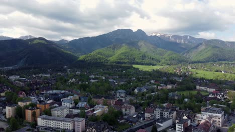 Flyover-of-Zakopane,-Poland,-a-resort-town-village-with-traditional-Goral-architecture-near-the-Polish-Tatra-mountains,-farmland,-forests,-Giewont-peak,-and-Great-Krokiew-Ski-Jump---4K-Tracking-Back-1