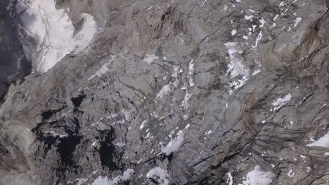 Look-down-view-from-drone,-pan-right,-at-rugged-Alps-terrain