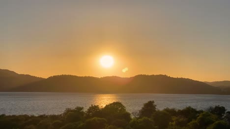 Wunderschöner-Und-Romantischer-Sonnenuntergang-Am-Meer-Mit-Etwas-Wind,-Der-Sich-Sanft-An-Der-Atlantikküste-Portugals-Bewegt,-Und-Der-Sonne,-Die-Hinter-Einem-Berg-Verschwindet