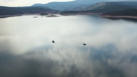 Beautiful-Sky-Reflection-On-Lake-Water-Surface-With-Boats-At-Flaming-Gorge-Reservoir,-Wyoming,-USA---aerial-shot