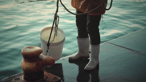 Fisherman-is-filling-a-bucket-full-of-seawater-and-pulling-it-out-on-the-platform-deck
