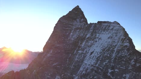 Die-Sonne-Späht-über-Den-Fernen-Kamm-Mit-Goldenen-Sonnenstrahlen,-Die-Das-Matterhorn-Beleuchten