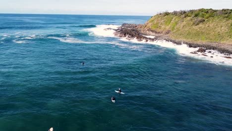 Drone-aerial-still-shot-of-surfers-waiting-in-line-up-on-headland-coastline-point-break-surfing-beautiful-landscape-tourism-Old-Bar-Point-Taree-NSW-Australia-4K