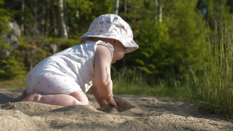 Cute-little-baby-child-playing-with-sand-outdoors-at-day