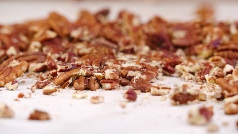 Whole-pecan-nuts-being-broken-into-tiny-crushed-pieces-by-mallet-in-slow-motion