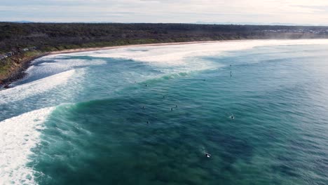 Drone-aerial-pan-landscape-scenery-shot-of-surfers-in-line-up-ocean-swell-waves-crystal-clear-tourism-travel-Old-Bar-Point-NSW-Taree-Australia-4K
