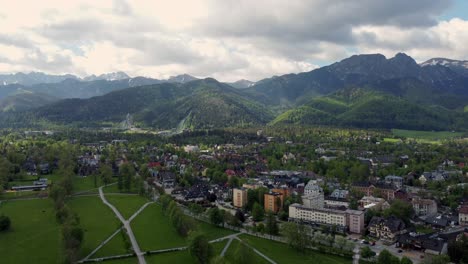 Flyover-of-Zakopane,-Poland,-a-resort-town-village-with-traditional-Goral-architecture-near-the-Polish-Tatra-mountains,-farmland,-forests,-Giewont-peak,-and-Great-Krokiew-Ski-Jump---4K-Tracking-Foward