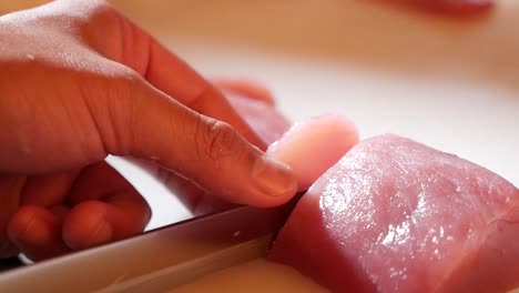 Hand-Use-Knife-to-Slice-Pink-Maguro-into-Small-Bite-Sashimi,-Close-Up-2